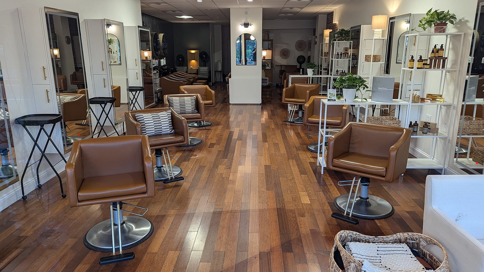 Row of styling stations with vanity mirrors and cognac leather chairs in a salon interior